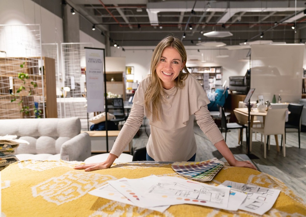 Interior designer reviews floor plans, fabric samples, and color palettes inside a modern furniture showroom.